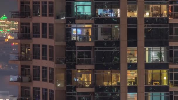 Reihen glühender Fenster mit Menschen in Mehrfamilienhaus in der Nacht. — Stockvideo