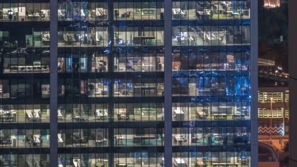 Immeuble de bureaux extérieur en fin de soirée avec lumières intérieures allumées et personnes travaillant à l'intérieur timelapse de nuit — Video