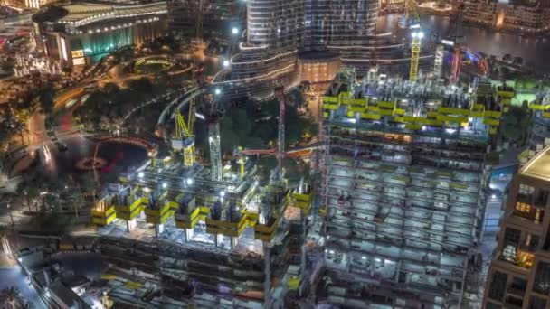 Vista aérea de un rascacielos en construcción con enormes grúas nocturnas timelapse en Dubai . — Vídeo de stock