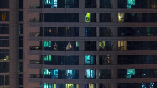 Рядки сяючих вікон з людьми в житловому будинку вночі . — стокове відео