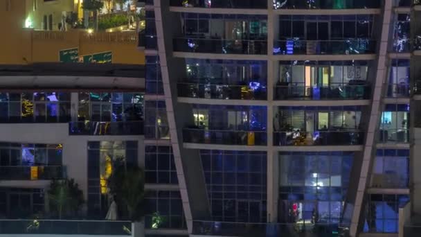 Filas de ventanas brillantes con gente en el edificio de apartamentos por la noche . — Vídeos de Stock