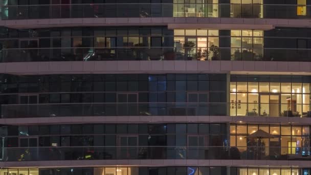 Filas de ventanas brillantes con gente en el edificio de apartamentos por la noche . — Vídeos de Stock