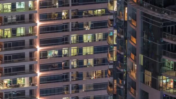 Fénylő ablaksorok emberekkel az apartmanházban éjszaka.. — Stock videók