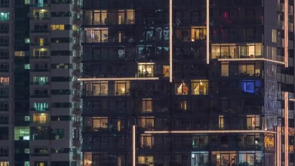 Rows of glowing windows with people in apartment building at night. — Stock Video