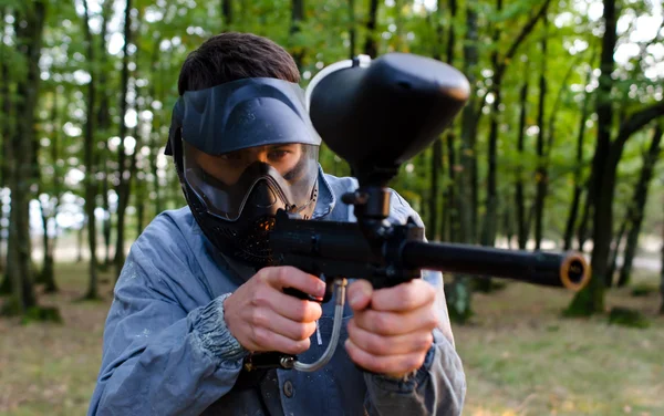 Człowiek shooter z paintball gun noszenia kasku ochrony i dir — Zdjęcie stockowe