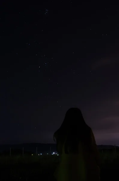 Teenage woman sit and look at night sky full of stars — Stock Photo, Image