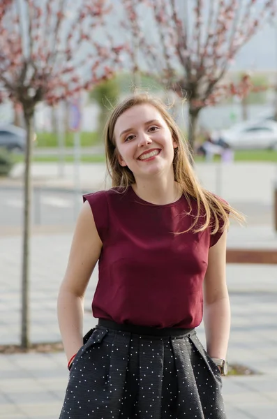 Joven mujer rubia pose al aire libre sonriendo con falda y tshir rojo Imagen De Stock