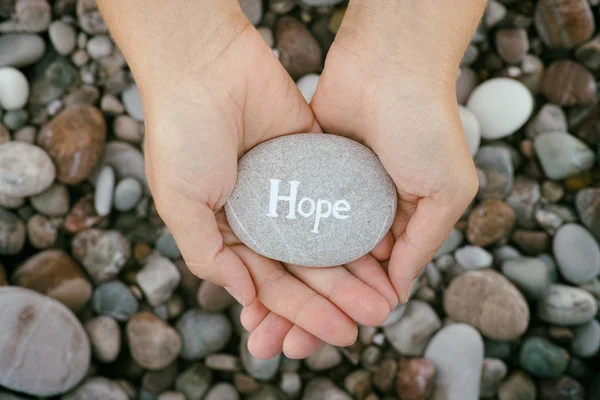 Mujer sosteniendo piedra con la palabra Esperanza en sus palmas — Foto de Stock