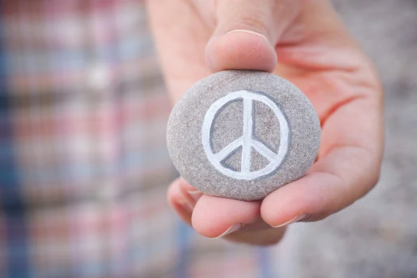 Pessoa segura pedra com símbolo de paz — Fotografia de Stock