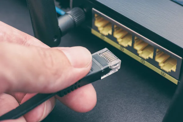 Person steckt Kabel an drahtlosen Router an — Stockfoto