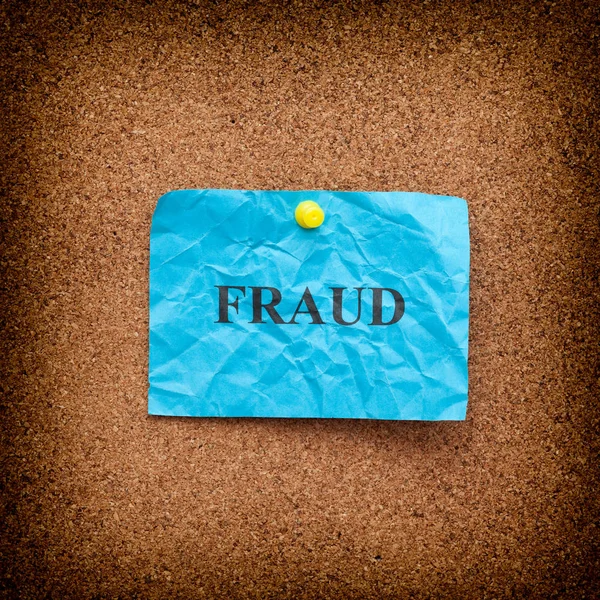 Fraud concept. Crumpled blue paper note with the word Fraud on cork board — Stock Photo, Image