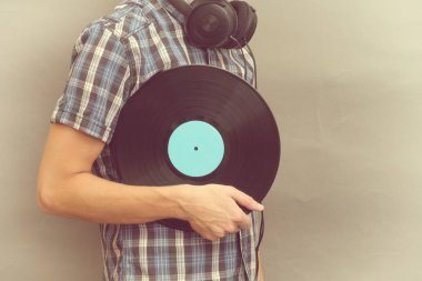 Adam kulaklık ile vinil rekoru elinde tutuyor.