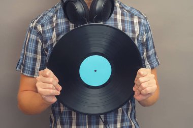 Adam kulaklık ile vinil rekoru elinde tutar.