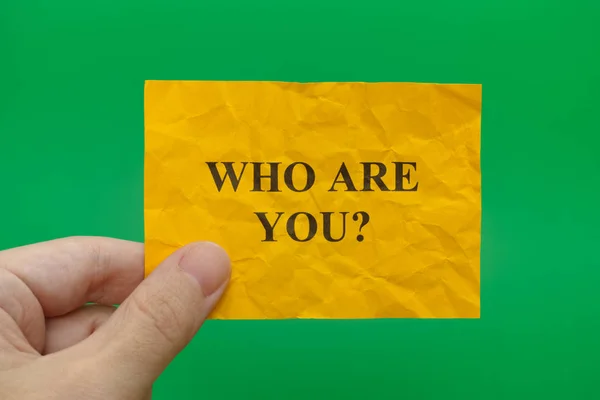 Человек, держащий желтую бумагу с вопросом: Кто ты? — стоковое фото