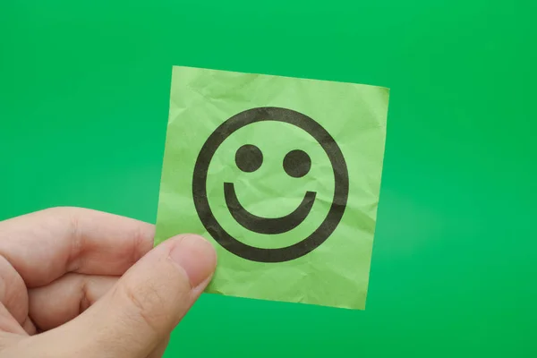 Человек, держащий зеленую бумагу с счастливым лицом — стоковое фото