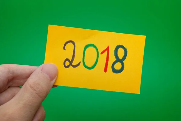 Pessoa segurando nota de papel amarelo com 2018 ano escrito nele — Fotografia de Stock