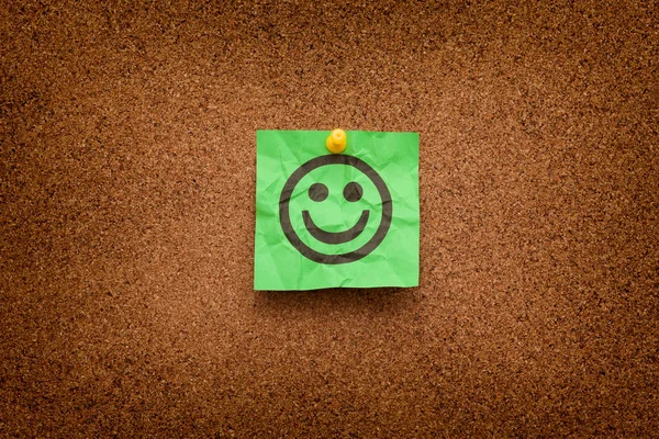 Crumpled Green paper with smiling face on corkboard — Stock Photo, Image