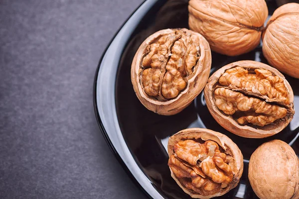 Walnuts in a black plate — Stock Photo, Image