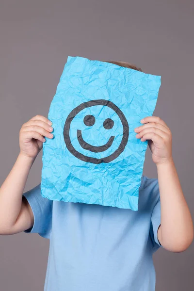Jonge jongen vel papier met smileygezicht houden — Stockfoto