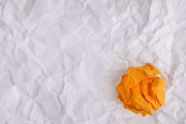 Gelbe Papierkugel auf zerknülltem Papierhintergrund — Stockfoto