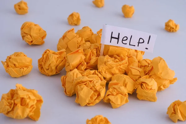 Yellow crumpled paper balls and flag with Help word written on it. — Stock Photo, Image