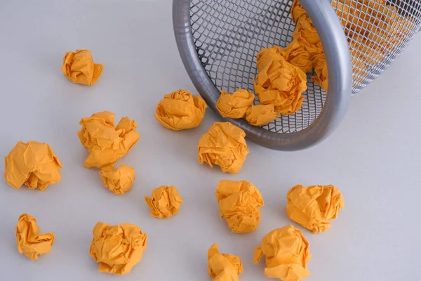 Gelbe zerknüllte Papierkugeln rollen aus einem Mülleimer — Stockfoto