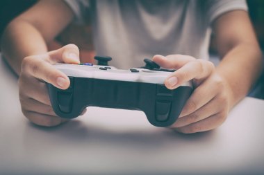 Genç çocuk bir gamepad kullanarak video oyunu oynar