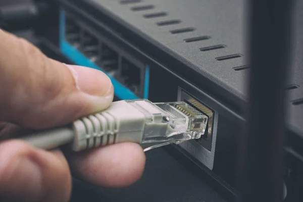 Person steckt Kabel an drahtlosen Router an — Stockfoto