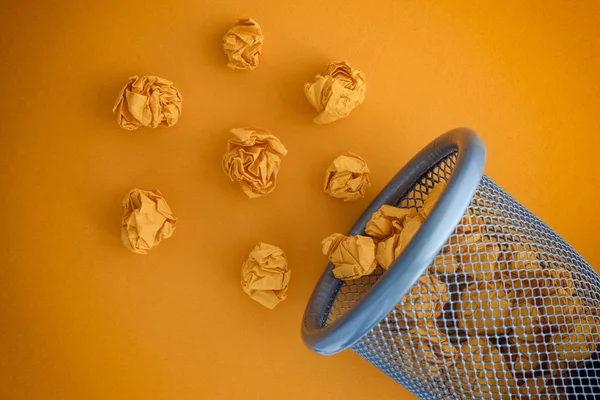 Gelbe zerknüllte Papierkugeln rollen aus einem Mülleimer — Stockfoto