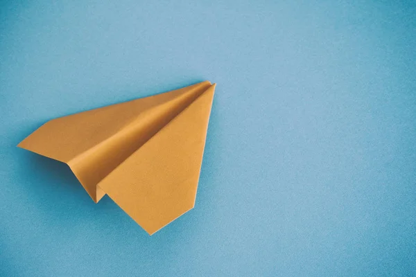Žluté papírové letadlo na modrém pozadí — Stock fotografie