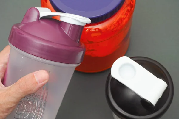 Person holds empty shaker in his hand above protein jar — Stock Photo, Image