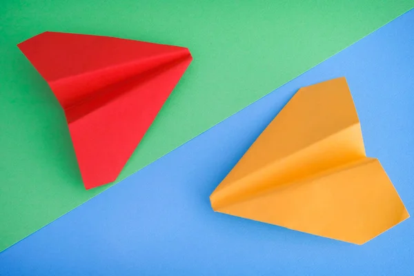 Aviones de papel amarillo y rojo sobre fondo azul y verde — Foto de Stock