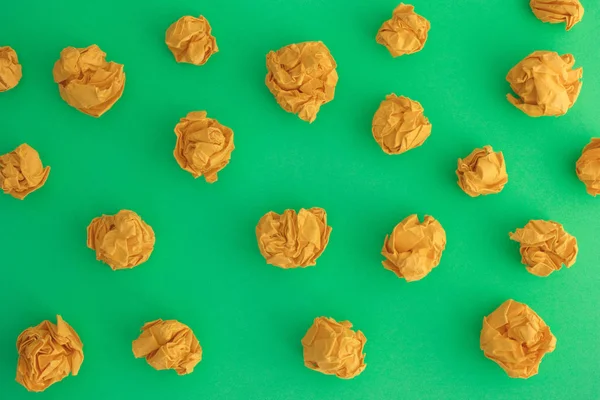 Bolas de papel arrugadas amarillas sobre un fondo verde — Foto de Stock