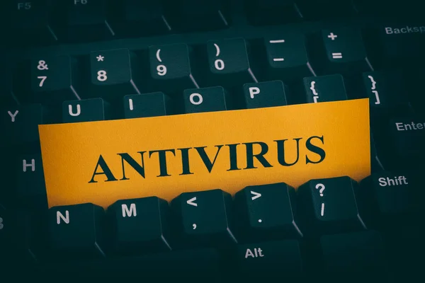 Yellow paper note on black keyboard with writing Antivirus — Stock Photo, Image