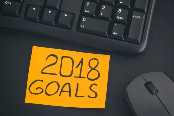 Nota di carta con scritta 2018 Obiettivi su una scrivania con tastiera nera — Foto Stock