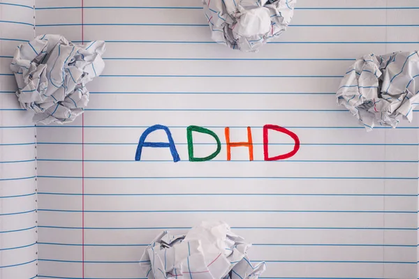 Abbreviation ADHD on notebook sheet with some crumpled paper balls on it — Stock Photo, Image