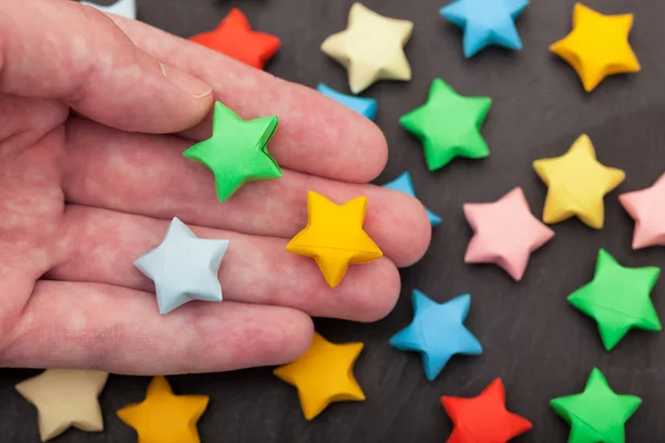 Colourful origami lucky stars in a palm — Stock Photo, Image