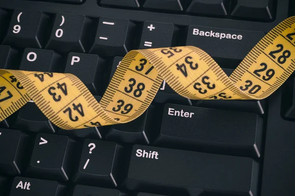 Černá počítače klávesnice a žluté Svinovací metr — Stock fotografie