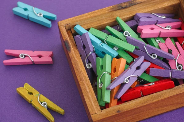 Pinzas de ropa de colores en una caja de madera sobre fondo púrpura —  Fotos de Stock