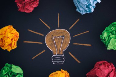 Çizim bir ampul ve renkli kağıt topları buruşuk