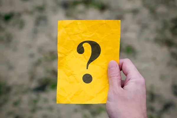 Mann mit gelbem Zettel mit Fragezeichen in der Hand — Stockfoto