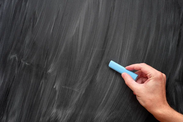 Hand mit blauer Kreide auf einer schwarzen Tafel — Stockfoto