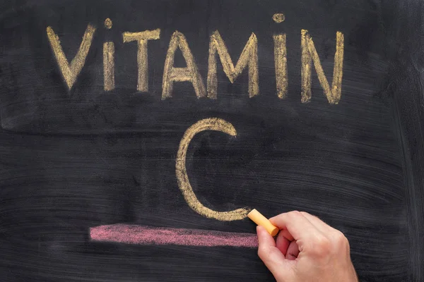 Man writing words Vitamin C on chalkboard — Stock Photo, Image