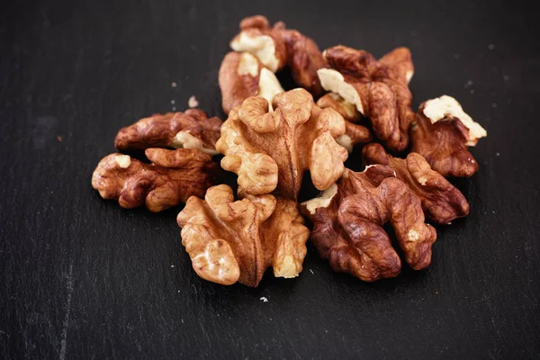 Organické syrové vlašské ořechy na břidlicovém pozadí — Stock fotografie