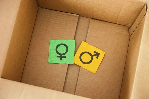 Crumpled colorful paper notes with gender symbols inside cardboa — Stock Photo, Image