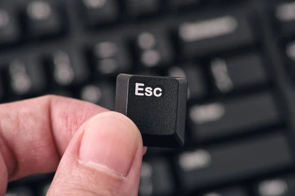 La mano del hombre sosteniendo la tecla Escape contra el teclado negro — Foto de Stock