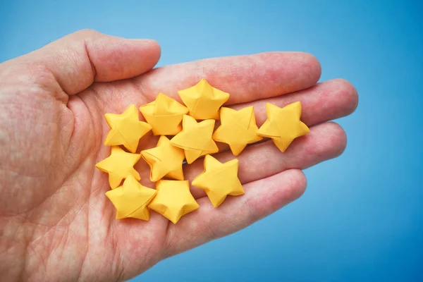 Yellow origami lucky stars in a hand — Stock Photo, Image