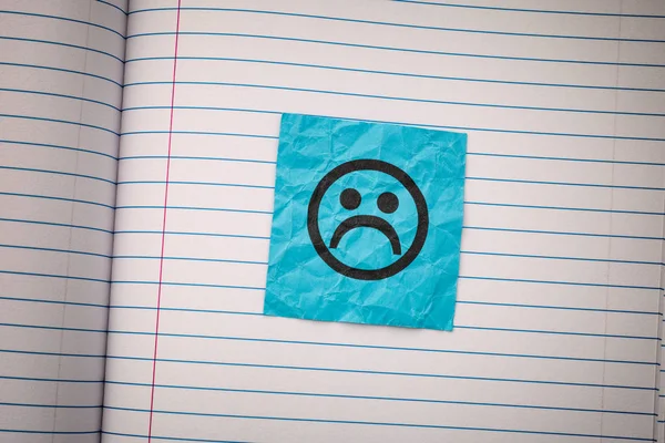 Niebieska kartka ze smutną twarzą na podszytym papierze — Zdjęcie stockowe