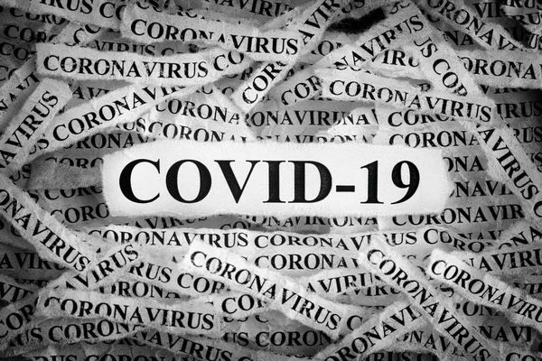 Strips of newspaper with the words COVID-19 and Coronavirus typed on them. Black and White. Close up.