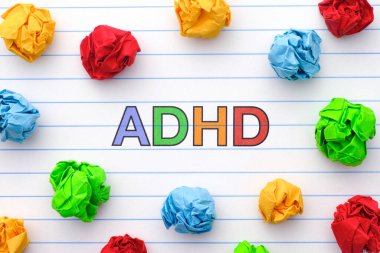 Dikkat eksikliği. Not defterindeki kısaltma ADHD. Etrafında renkli buruşmuş kağıt toplar var. Kapatın. Dikkat eksikliği hiperaktivite bozukluğudur..